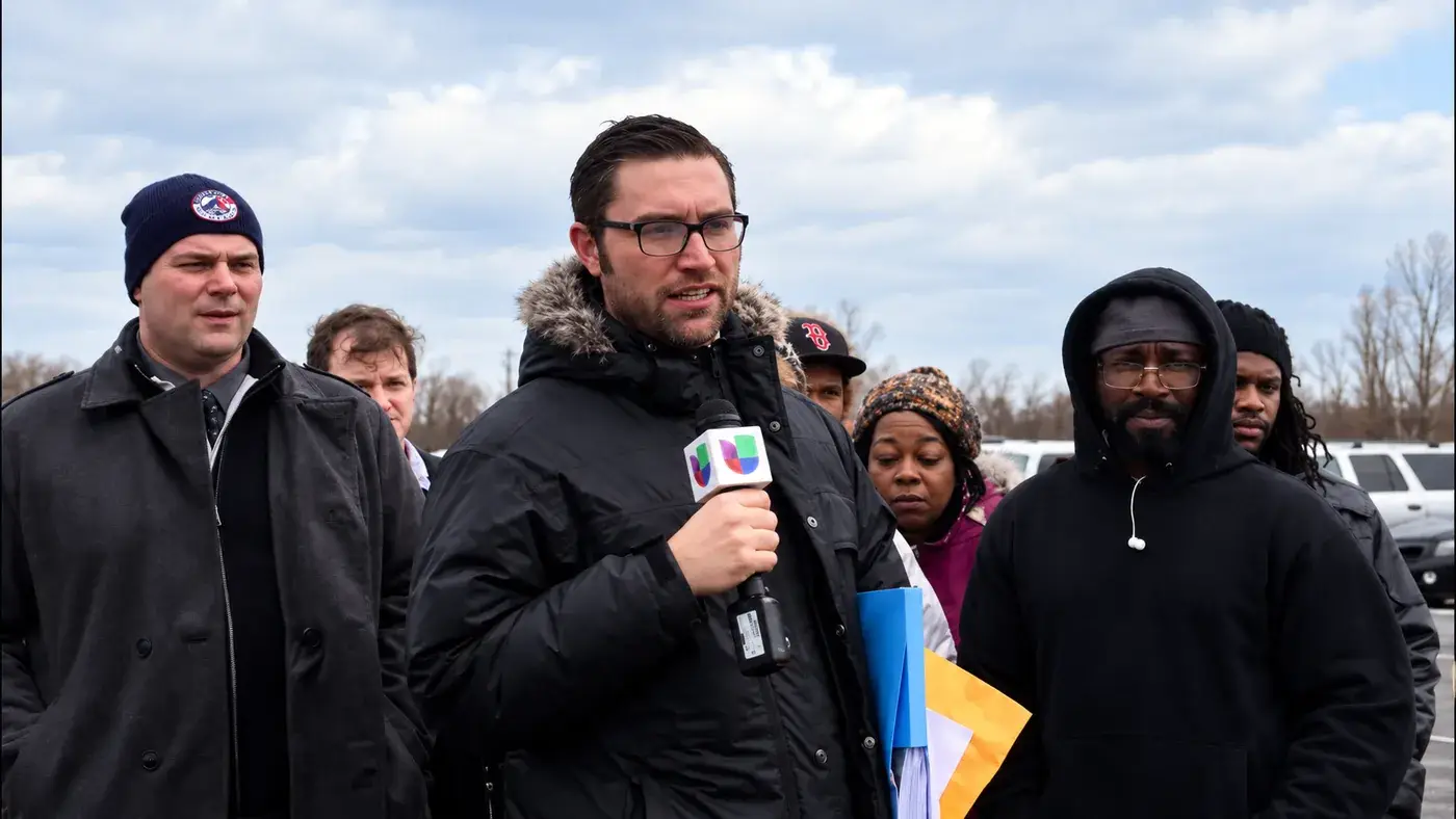 Nick Kreitman speaking to reporters with truck drivers at a truck yard